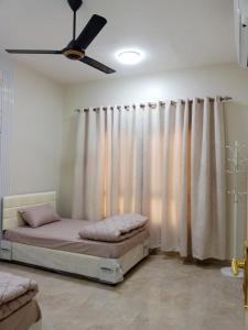 a bedroom with a bed and a ceiling fan at Al Khashabah Apartment شقة في طريق إزكي - سناو in Mukhtari‘
