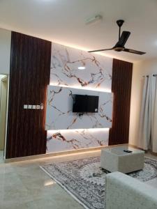 a living room with a tv on a wall at Al Khashabah Apartment شقة في طريق إزكي - سناو in Mukhtari‘