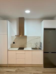a white kitchen with a sink and a refrigerator at Apartamentos HORNOS in Hornos +6 photos