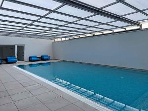 a large swimming pool with blue chairs in a building at Feel So Good Apartment with Sea View Hot Tub in Sesimbra
