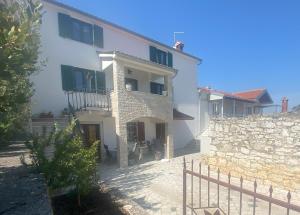 a large white house with a stone wall at Appartments Grgeta in Funtana