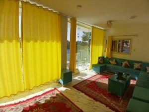a living room with yellow curtains and a green couch at Esmerada in Aswan