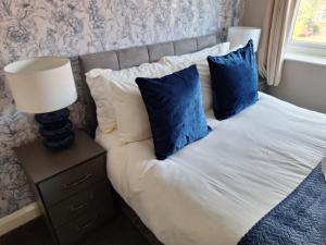 a bed with blue pillows and a lamp on a night stand at Fieldside House in Scarborough