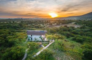 a house in a field with the sunset in the background at Kitumo Mara Lodges in Mara Simba