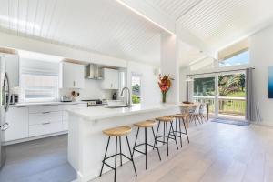 a kitchen with white cabinets and bar stools at Hale Mauna Nui in Princeville