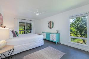 a white bedroom with a bed and a window at Hale Mauna Nui in Princeville