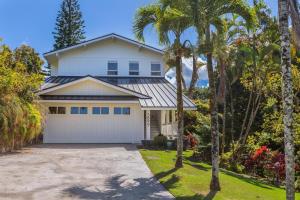 a white house with palm trees and a driveway at Hale Mauna Nui in Princeville