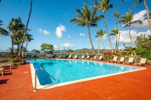 a swimming pool with chairs and palm trees at Lae Nani 434 in Kapaa