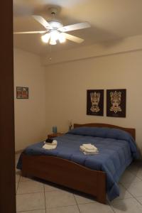 a bedroom with a blue bed with a ceiling fan at Appartamenti la vuci in Partanna