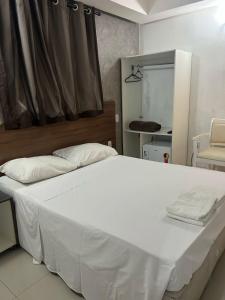 a bedroom with a large white bed and a mirror at HANNA Arcos d'Atalaia Hotel - Aracaju in Aracaju