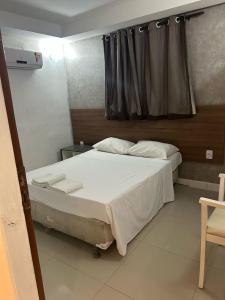 a bedroom with a bed with white sheets and a window at HANNA Arcos d'Atalaia Hotel - Aracaju in Aracaju