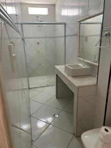a white bathroom with a shower and a sink at HANNA Arcos d'Atalaia Hotel - Aracaju in Aracaju