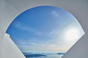 una ventana circular con vistas al cielo en La Maltese Caldera Concept, en Imerovigli