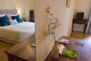 a bedroom with a bed and a vase on a table at Les Hospitaliers in Le Poët-Laval