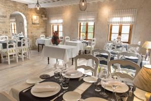 a dining room with white tables and white chairs at Les Hospitaliers in Le Poët-Laval