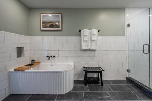 a white bathroom with a tub and a stool at New Remodel! 4BR Near DT Cartersville & Major Hwys in Cartersville +34 photos