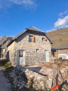a stone building with a door on the side of it at Family Apartment Na krovu svijeta in Lukomir