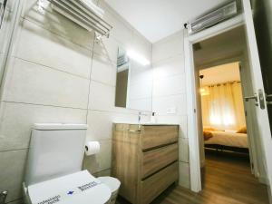 a bathroom with a toilet and a sink and a bed at Apartamento Puerta de Madrid 2 in Alcalá de Henares +17 photos