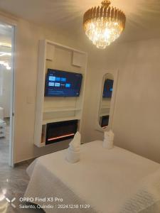 a bedroom with a bed and a tv and a chandelier at Aparta Hotel Boutique Salento in Salento