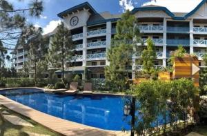 a hotel with a swimming pool in front of a building at Pine suite Condo Tagaytay in Tagaytay