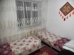 a bedroom with two beds and a window with curtains at Hostel ASMAN in Kochkor +6 photos