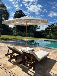 an umbrella and two lounge chairs next to a pool at Pousada Villa Dois Amores in Lindóia +26 photos