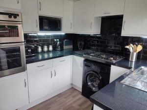 a kitchen with white cabinets and a washing machine at 4-bed quiet cul de sac location with large secure off road parking for 4 cars in Timperley