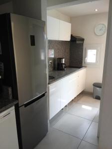 eine Küche mit weißen Schränken und einem Kühlschrank in der Unterkunft superbe appartement vue port in Leucate-Plage