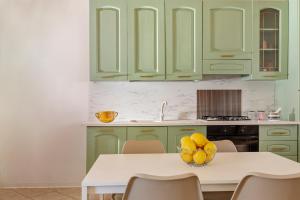 a kitchen with green cabinets and a table with a bowl of fruit at Case Vacanza Loria in Castelluzzo