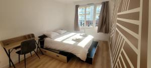 ein Schlafzimmer mit einem Bett, einem Schreibtisch und einem Fenster in der Unterkunft Appartement Hyper-Centre 3 Chambres 3 Salles de Bain Parking in Saint-Nazaire