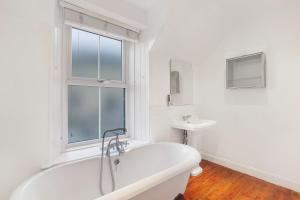 une salle de bain blanche avec une baignoire et un lavabo dans l'établissement Grove Cottage - North East Escapes, à Bamburgh 27 autres photos