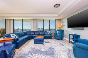 ein Wohnzimmer mit blauen Sofas und einem Flachbild-TV in der Unterkunft Phoenix on the Bay 1333 - Poseidon House condo in Orange Beach