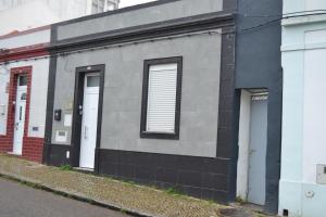 un edificio grigio con due porte bianche su una strada di O Chalé Bela a Setúbal