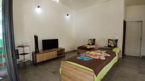 two beds in a room with a tv and a room with two beds at Tahiti Iti - Fare Pihiti Spot in Paui