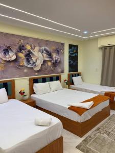 カイロにあるGarden City inn Hotelのベッドが3つあり、壁に絵が飾られている部屋