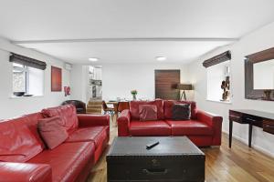 a living room with two red couches and a piano at Barn Cottage - North East Escapes in Bamburgh +34 photos