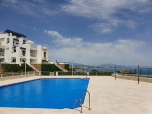 a blue swimming pool in front of a building at First line beach 2bedrooms appartment in Casares
