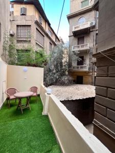 a small balcony with green grass and a table and chairs at Triple Garden Studios and apartments in Cairo