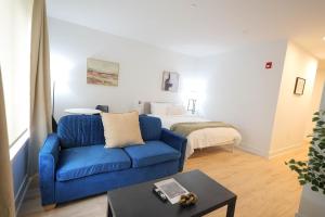 a living room with a blue couch and a bed at The Platinum Downtown Stamford Studio Getaway in Stamford