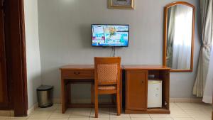 a room with a desk and a television on a wall at Hotel Peninsule Bonamoussadi Douala in Douala