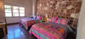 a bedroom with two beds and a brick wall at Sandy Shores Cabaña 8A in La Paz