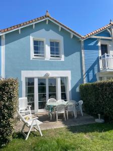 ein blaues Haus mit einem Tisch und Stühlen davor in der Unterkunft La Petite Maison bleu in Talmont