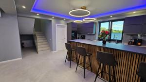 una cucina con armadi viola e un bar con sgabelli di Vila LakeView Snagov, Terasă pe Acoperiș, Self Check-in, Parcare Privată a Snagov