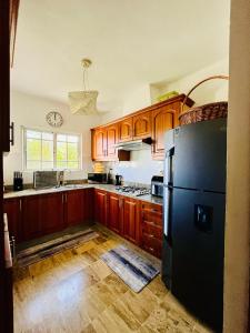 a kitchen with wooden cabinets and a black refrigerator at Apartamento en Punta Cana, White sands in Punta Cana