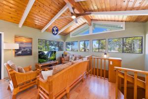 a living room with wooden ceilings and windows at Pu'u Nui in Waikoloa Village