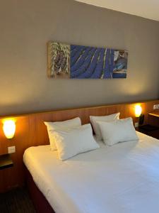 a large white bed with two pillows on it at Kyriad Martigues Sud in Martigues