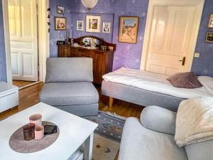 a living room with purple walls and a bed and a chair at 4 person holiday home in SKÄRHAMN in Skärhamn