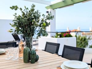 a wooden table with a vase with flowers on it at Beautiful first line Penthouse with Sea View Mi Capricho in Mijas Costa