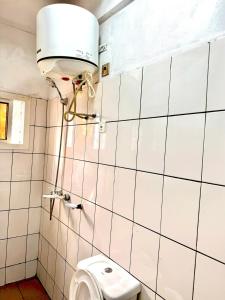 a bathroom with a toilet and a light on the wall at Santa-Barba brand new apart Yde in Yaoundé