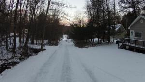 a road covered in snow in front of a house at Wallenpaupack Lake house in Greentown